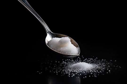Spoon with sugar on a black background