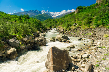 Stormy mountain river flowing among the stones against the backdrop of the extinct volcano Kazbek....
