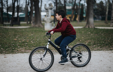 A boy takes pleasure in cycling through a green park, experiencing the freshness and freedom of the outdoors.