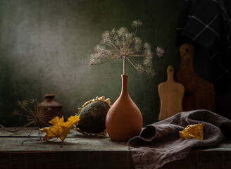 Autumn still life with a dry branch in a clay vase on a dark background
