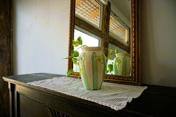 Innenausstattung mit weißer Häkeldecke, grün-weißer Keramikvase mit Pflanzenzweigen mit grünen...