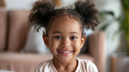 Smiling cute little African American girl with two pony tails looking at camera. Portrait of happy female child at home. Smiling face a of black 4 year old girl looking at camera with afro puff hair. - obrazy, fototapety, plakaty