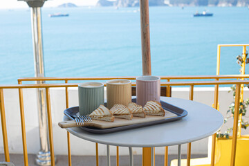 a tray with a breakfast on an outdoor terrace and the sea in the background.