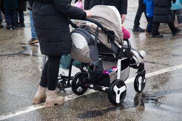 A young mother and a baby carriage.A girl with a baby in a stroller.