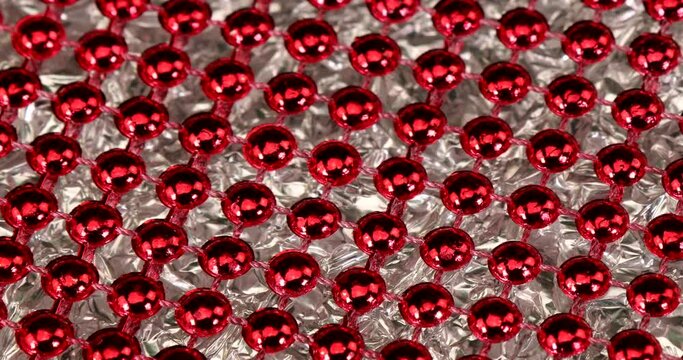 Structure with red shiny beads in front of a silver glass rotating background