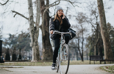 Cheerful young woman enjoying a leisure bike ride in the park during autumn.