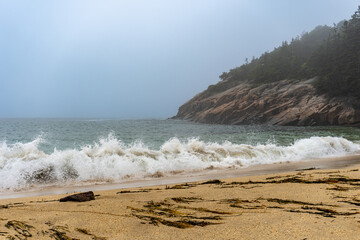 Crashing waves on Sand Beach in Acadia National Park, Maine. Surrounded by cliffs, this small stretch of coast is the largest sandy beach in Acadia. Rough surf on foggy, stormy day.