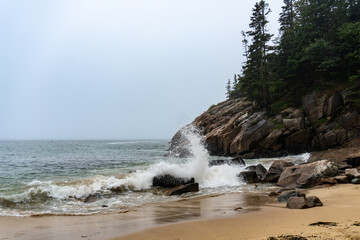 Crashing waves on Sand Beach in Acadia National Park, Maine. Surrounded by cliffs, this small stretch of coast is the largest sandy beach in Acadia. Rough surf on foggy, stormy day.