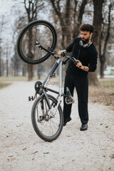 A businessman in formal attire takes a leisurely break, fixing his bicycle in a serene park setting, balancing work and well-being.