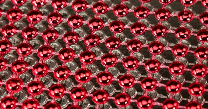 Fabric with red and silver shiny beads in front of a glass rotating background