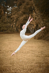 Full length portrait of young hairless girl ballerina with alopecia in tight white suit jumps on...