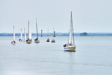 Parade of yachts along shore, several motor sailers yachts sailing along coast with lowered sails...