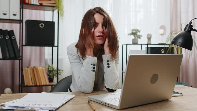 Tired sleepy young businesswoman sitting at home office desk with laptop overworked lazy bored lady worker feel fatigue exhausted of work deprived. Exhausted workaholic freelancer workaholic girl