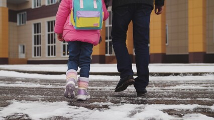 legs close-up, walking snow, child his father walk with their feet snow school building, child...