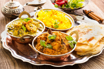Traditional Indian curry dishes served with saffron rice and pita bread as close-up on a design...