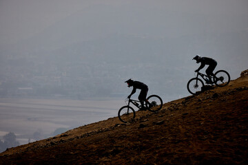 Downhill bike riders descending the lines of Morro Solar at Chorrillos With Lima city on the background