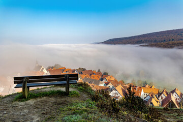 Empty bench on the top of the hill against the background of the city covered with fog, beautiful landscape.