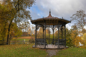 Panoramic view of metal openwork gazebo in public park in autumn