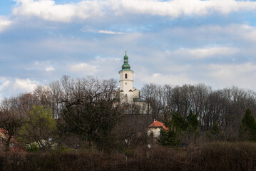 A small church on a hill among trees against a blue sky