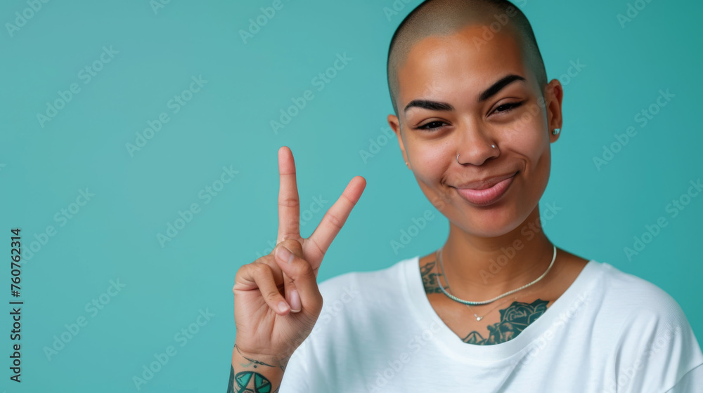 Wall mural confident young woman with a buzz cut, winking and making a peace sign with her fingers, set against