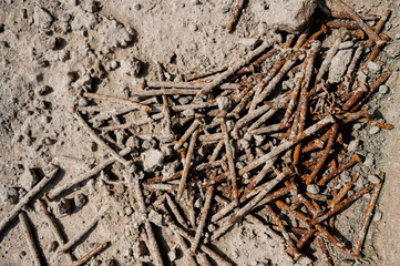 Used nails waste at construction site which rusted and covered in cement concrete.