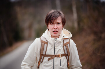 A young adult appears troubled while hiking alone on a forest path, capturing a moment of...