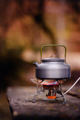 A sturdy kettle stands on a compact gas stove, surrounded by soft, natural hues, capturing the essence of outdoor adventure and self-sufficiency