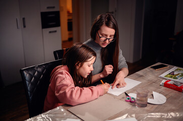 A mother and daughter engage in a crafting activity at home, highlighting the importance of quality family time and the joy of creative pursuits together
