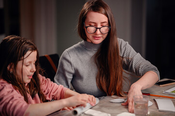 An engaging scene of a girl and a woman working together on a crafts project, with their hands...