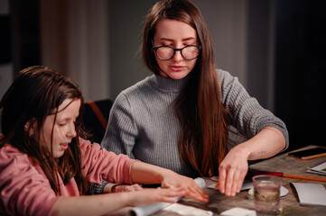 Fototapeta premium An engaging scene of a girl and a woman working together on a crafts project, with their hands busily at work amid various materials