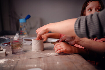 Close-up of a child's hands carefully assembling a clay craft, symbolizing the intricate beauty of learning and creating