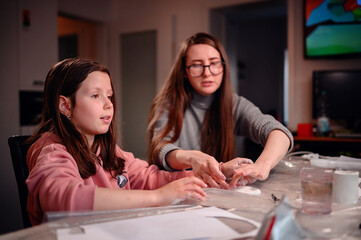 The sheer delight of a girl sculpting with clay is shared with her mother, capturing the essence of...