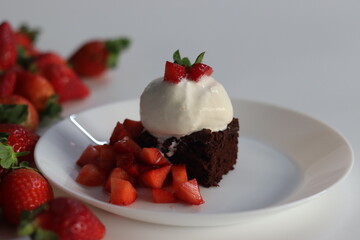 Chocolate brownie with fresh strawberries and a scoop of creamy vanilla ice cream