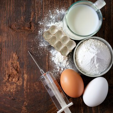 Baking background. Milk, flour, eggs and confectionery syringe for cake. On a rustic background.