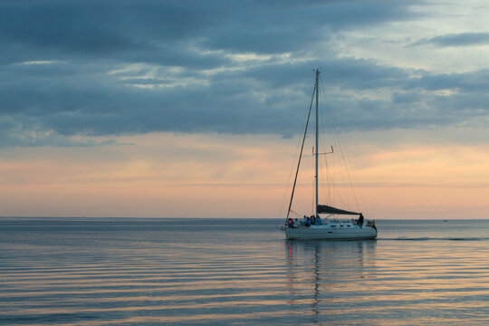 Long exposure image of dramatic sky seascape with a sailing yacht in sunset scenery background and a sailing yacht
