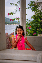 Beautiful Young Indian girl smiling  and dressed up in traditional indian Rajasthani wear in a royal background 