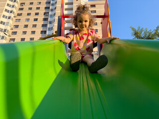 Little curly haired girl going down a kid's slide