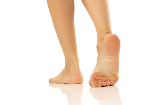 Closeup of female bare feet standing on white background