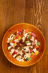 Mix of dried fruits and nuts on a wooden plate on the table. Vertical