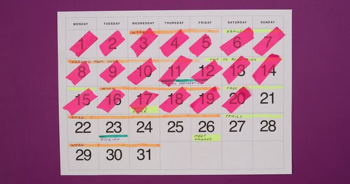 Monthly calendar planning with colorful highligted notes and reminders. Time management and planning concept. Top view, 4K stop motion animation.