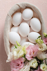 Fototapeta na wymiar A bouquet of pink and white eustoma flowers and chicken eggs in a basket. Easter background.