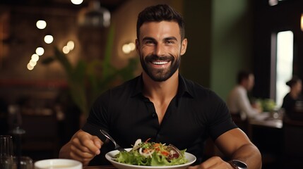 Portrait of a happy man sitting at a table behind a plate of green salad. Smiling cheerful man eating salad in a restaurant on a blurred background. Fat man eating a healthy lunch meal in a cafe. - 760796589