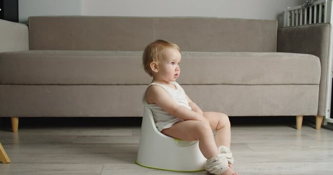 Side view of adorable smiling girls sitting on chamber pot,potty training hygiene. child learning sit on toilet wc seat at home. Kid about two years old. High quality 4k footage