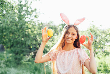 Cute funny girl with Easter eggs and bunny ears at garden. easter concept. Laughing child at Easter egg hunt. Child in park with basket full of eggs, spring concept - 760813940