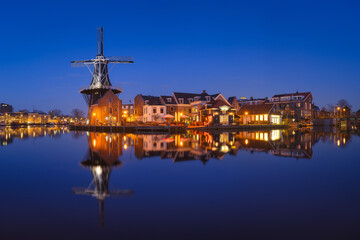 The windmill De Adriaan, Haarlem, Netherlands. Historic buildings. Cityscape during the blue hour. Reflections on the surface of water. Panorama. Picture for background and wallpaper. - 760814931