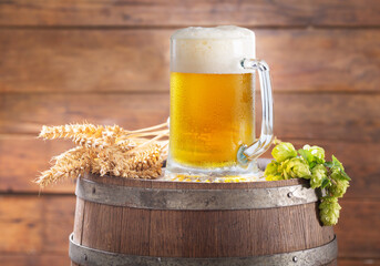 Mug of beer with wheat ears and green hops on  wooden barrel - 760815107