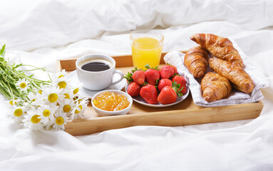 Breakfast in bed. Tray with cup of coffee, croissants, orange juice, fresh fruits and bunch of daisy flowers - 760815116