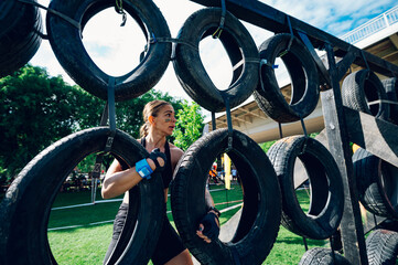 Woman passing wall made with car tires while participating in an OCR race