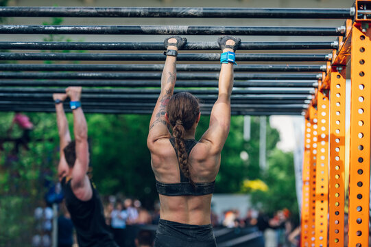 Strong muscular female participating in an obstacle course race outdoor