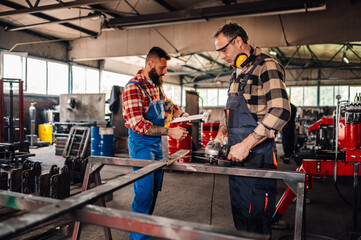 Two craftsmen in a metal workshop getting ready for grinding material.